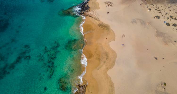 Vue aérienne de plage de sable et d'eaux claires.