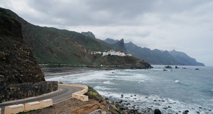 Paysage côtier avec des falaises rocheuses et un petit village au loin.