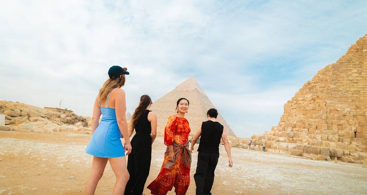 Groupe de personnes près des pyramides avec un ciel bleu clair.
