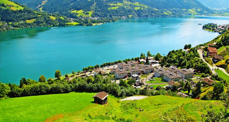 Una vista elevada de un pueblo junto a un gran lago rodeado de colinas.