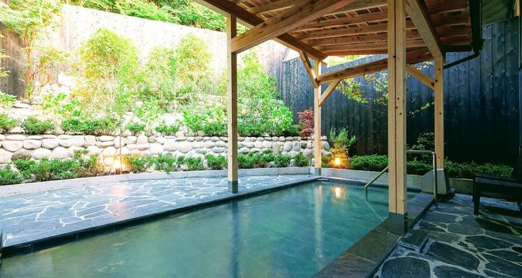 Onsen en plein air avec vue sur jardin.