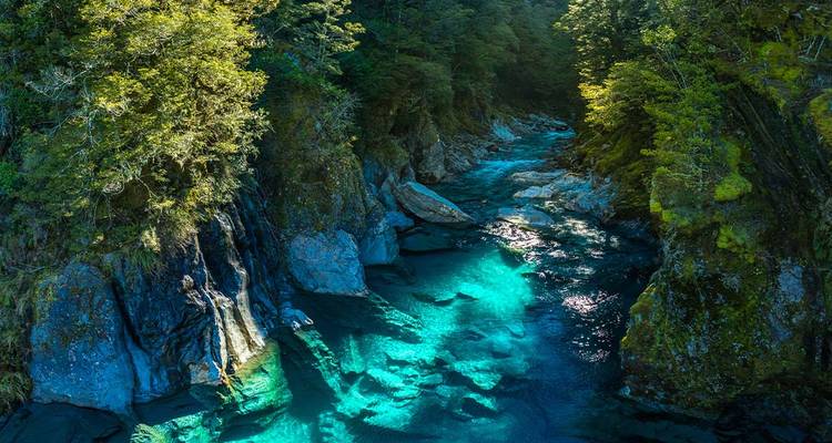 Rivière bleu cristallin qui traverse un canyon boisé.
