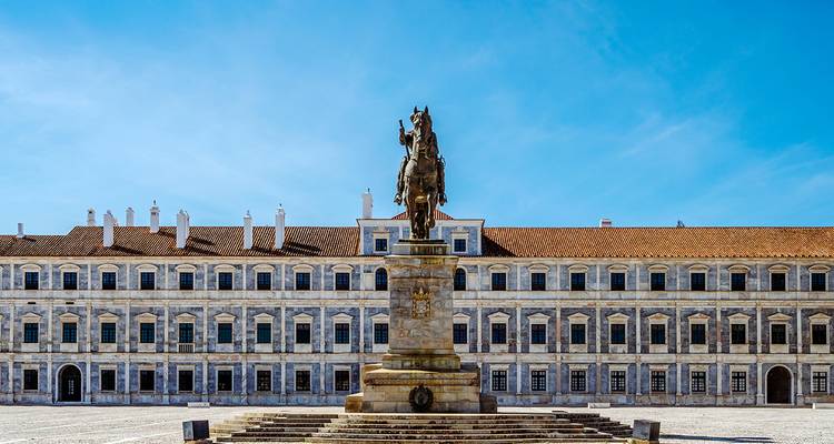 A large equestrian statue in front of a historic building.
