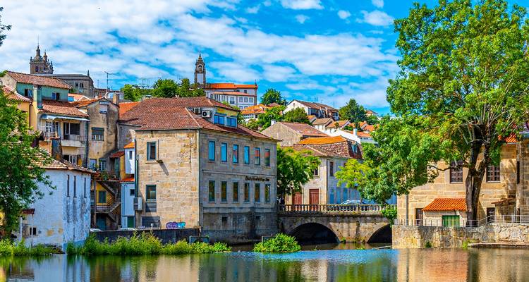 A scenic riverside town with traditional European architecture and a bridge.