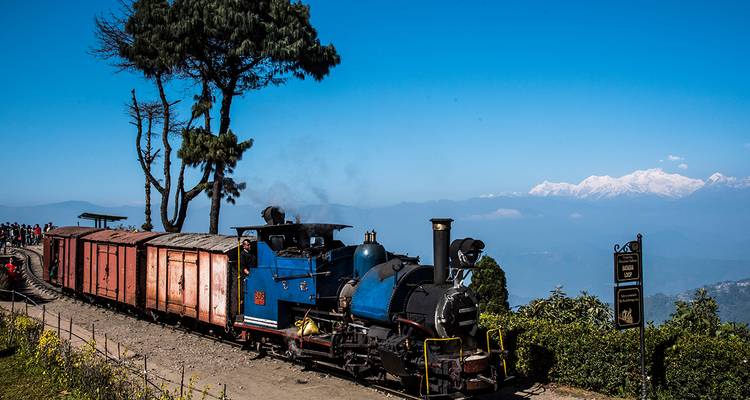 Train jouet roulant sur des rails avec vue sur la montagne.