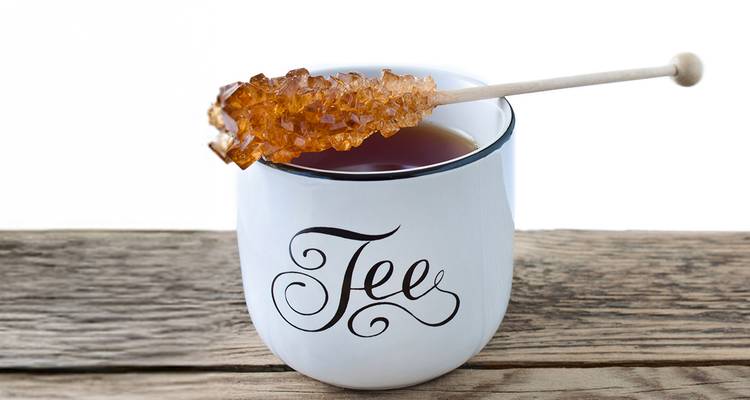Tasse étiquetée 'Tee' avec un bâton de sucre candi sur une surface en bois
