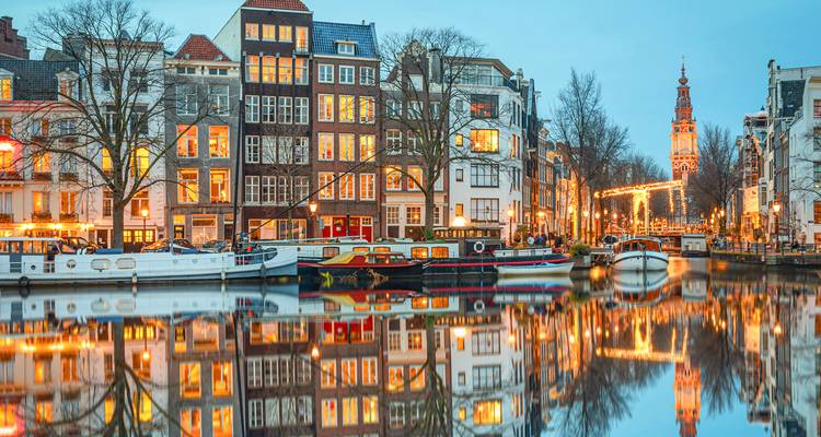 Canal con reflejo de edificios bellamente iluminados en Ámsterdam.