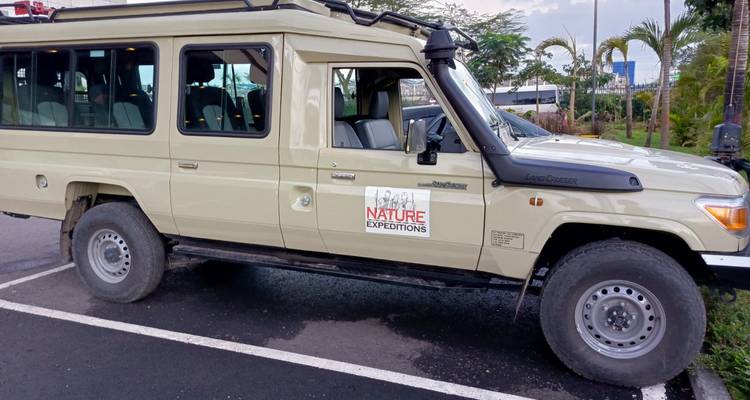 Un véhicule de safari garé avec un panneau pour des expéditions nature.