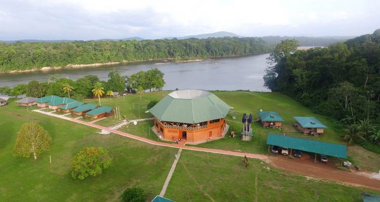 Aerial view of a complex with green-roofed structures by a river.