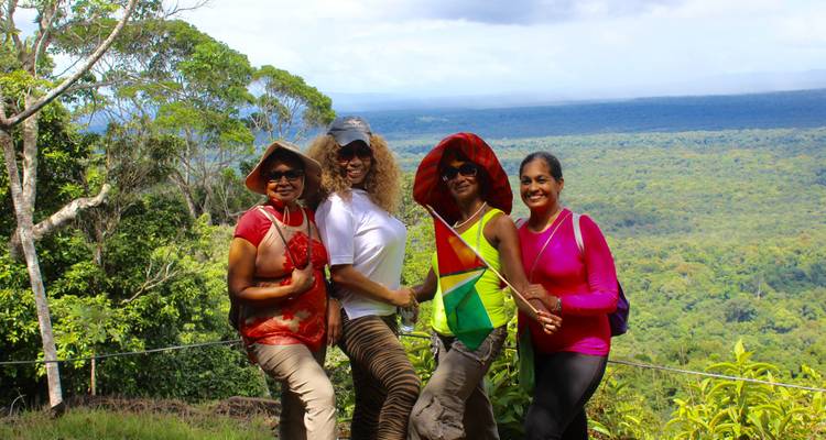 A group of four women posing with a forested landscape backdrop.