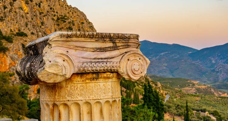 Close-up of a classical Greek column with a mountainous backdrop.