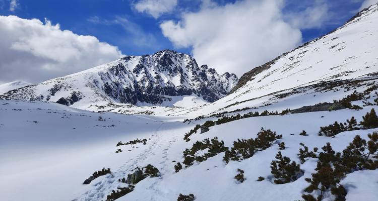 Snowy mountainous landscape under a partly cloudy sky.