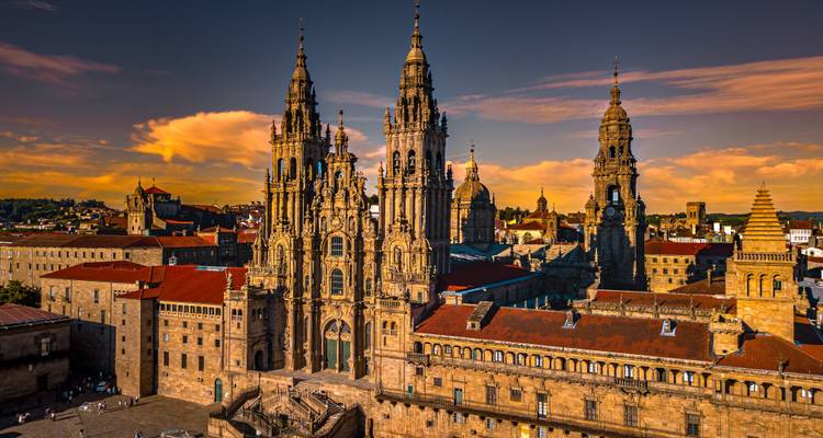 La magnifique cathédrale de Santiago de Compostela brillant au coucher du soleil avec des nuages orange dramatiques au-dessus.