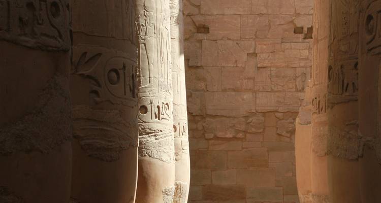 Colonnes sculptées avec hiéroglyphes et ombrage partiel.