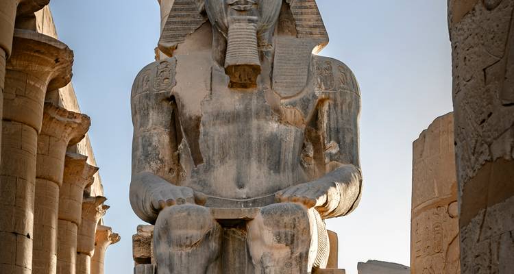 Statue d'un pharaon assis avec des colonnes inscrites d'hiéroglyphes.