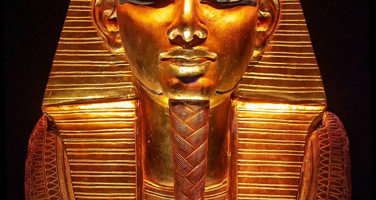 Masque doré d'un pharaon égyptien sur un fond sombre.