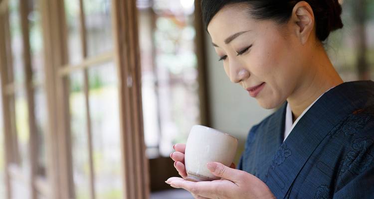 Femme en tenue traditionnelle savourant une boisson.
