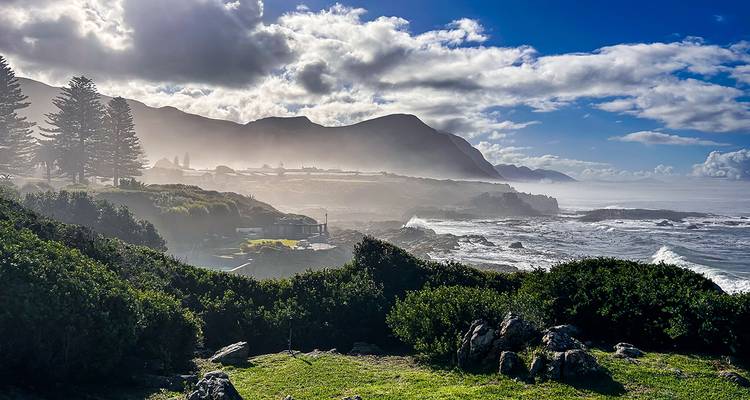 Paysage côtier avec collines brumeuses et vagues qui se brisent.