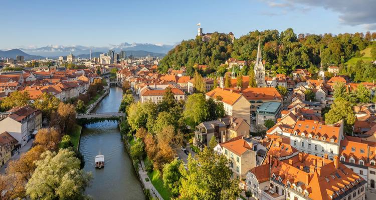 Europees stadslandschap met een centrale rivier en kasteel op een heuvel.
