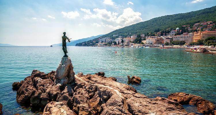 Kustplaats met een bronzen standbeeld op rotsen.