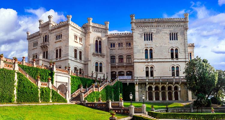 Sierlijk kasteel met weelderige tuinen en met klimop begroeide gevel.
