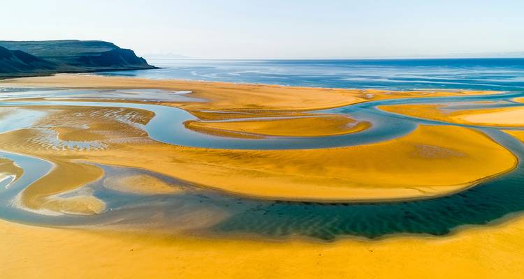 Vaste littoral sablonneux avec des cours d'eau serpentins.