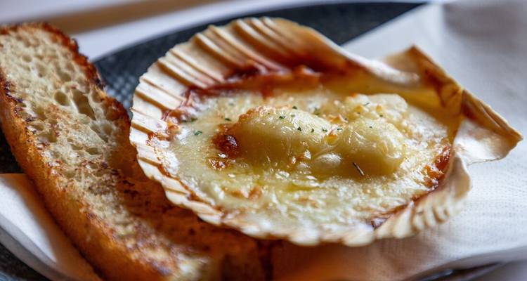 Coquille Saint-Jacques gratinée au fromage servie avec du pain