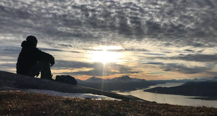 Personne assise sur un rocher regardant un ciel dramatique au-dessus de la mer