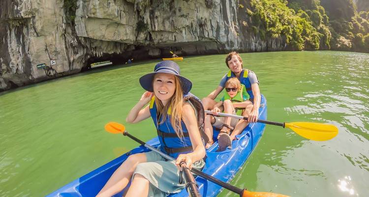 Une famille faisant du kayak dans une grotte pittoresque avec des gilets de sauvetage.
