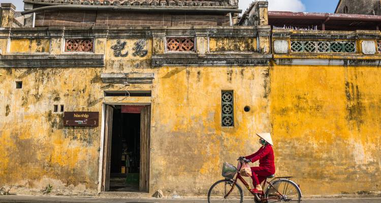 Personne faisant du vélo devant un ancien bâtiment jaune.
