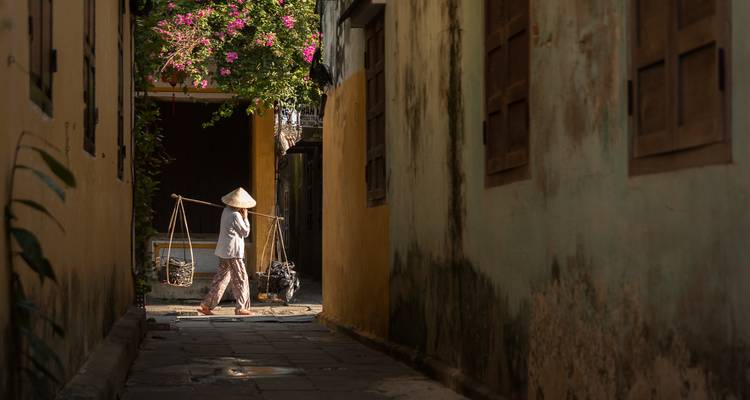 Personne marchant dans une ruelle étroite avec un joug.