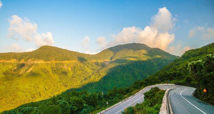Route panoramique serpentant à travers les montagnes vertes.