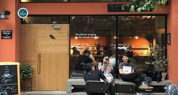Des personnes dans un café posant dehors avec un logo sur le bâtiment.