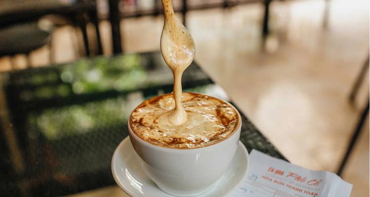 Gros plan d'une tasse de café avec mousse sur le dessus.