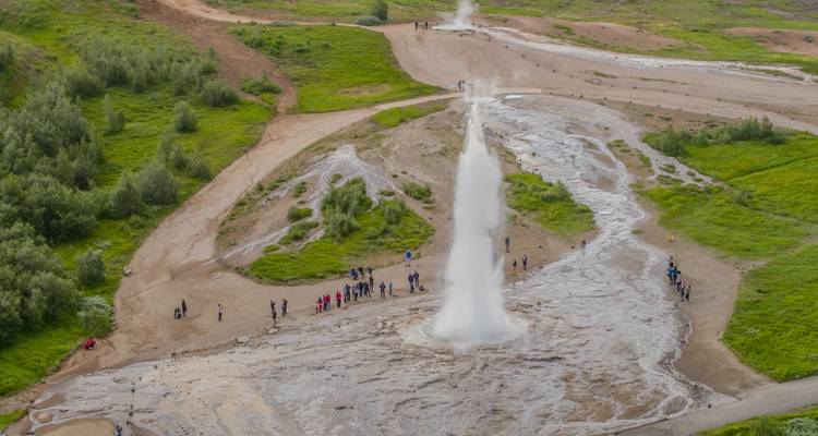 A geyser erupting in a natural park setting.