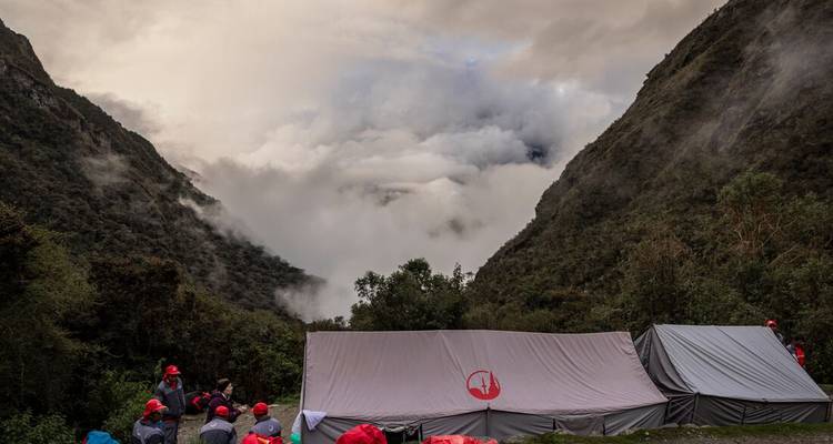 Camping de tentes dans une vallée avec des nuages qui descendent.