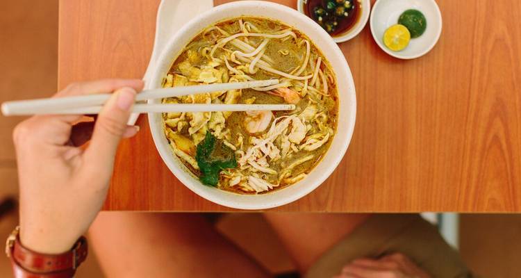 Gros plan d'un bol de soupe avec des baguettes.