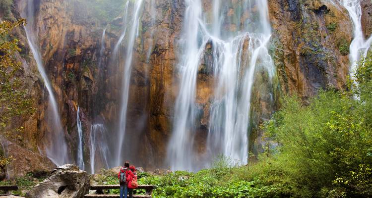 Personne debout devant une grande cascade.