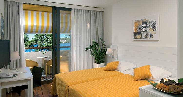 Une chambre d'hôtel avec lits jumeaux et vue sur balcon.