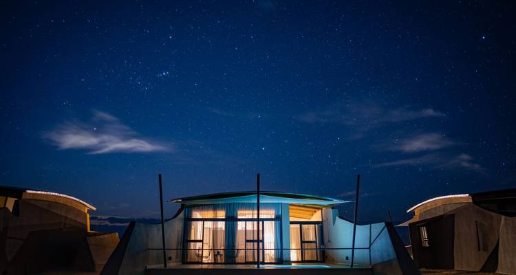 Modern desert lodge glowing under a brilliant starry night sky.