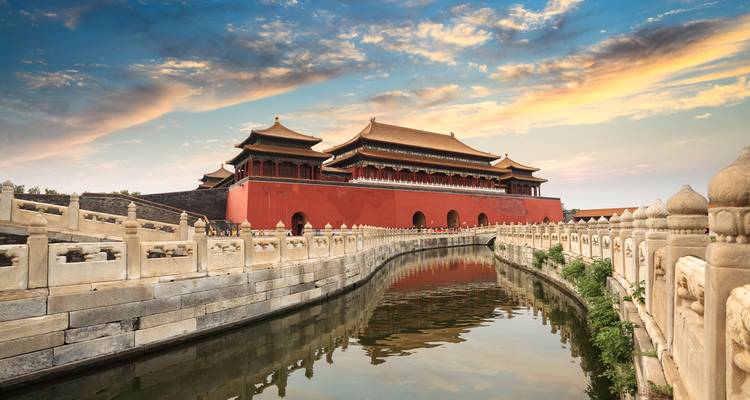 View of the Forbidden City with a canal and bridge, under a stunning sky.