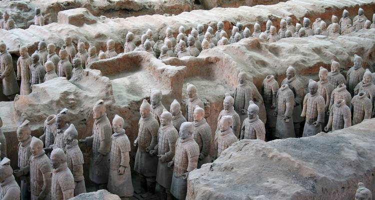Terracotta warriors lined up in an excavation site.
