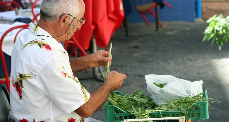Homme à un marché de rue avec des légumes verts frais.