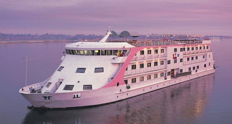 Gran crucero moderno del Nilo navegando en aguas tranquilas del río bajo cielos rosados del crepúsculo.