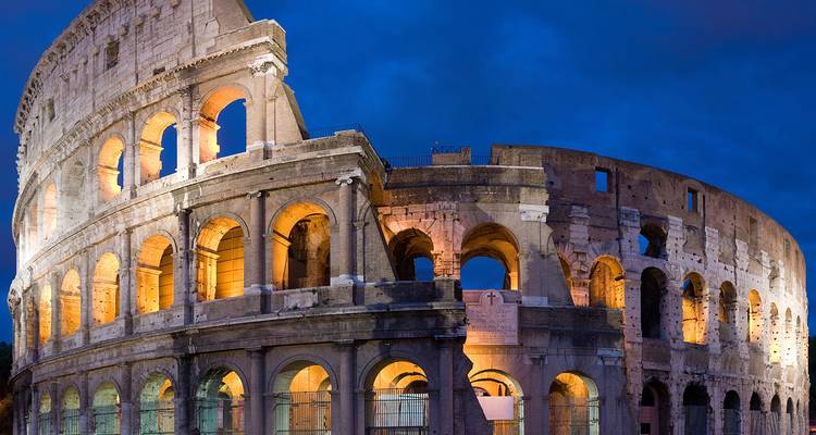 Het verlichte Colosseum staat majestueus tegen een diepblauwe avondhemel.