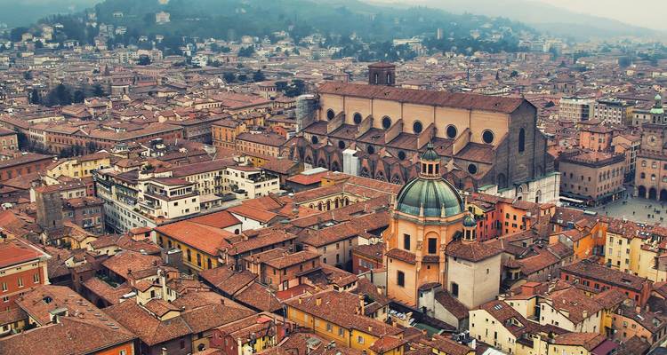 Imagen aérea de los tejados de tejas rojas de Bolonia con la Basílica di San Petronio dominando el centro.