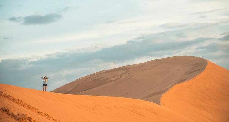 Person standing on large sand dunes.