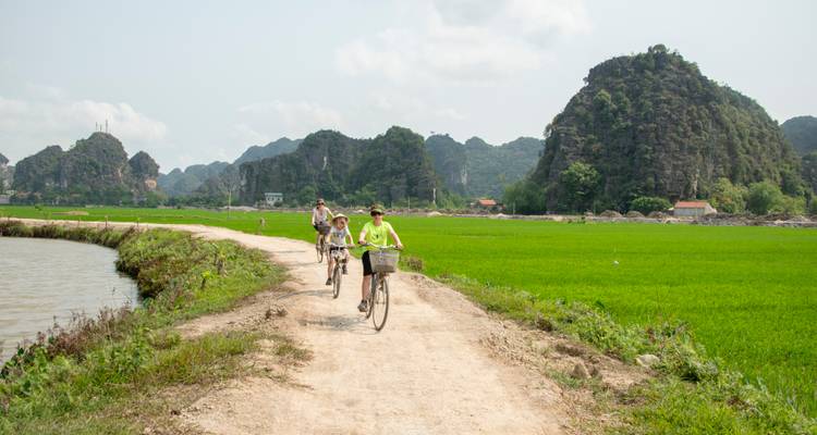 People cycling on a rural path with mountains.