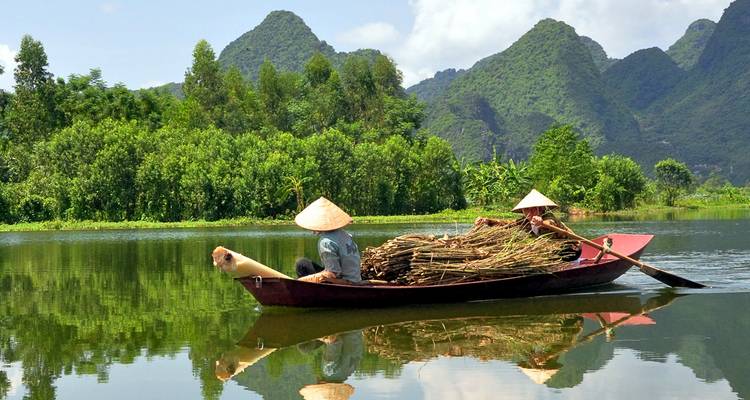 Two men rowing a boat in a lush green landscape.