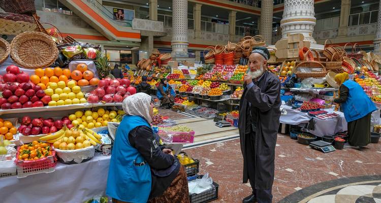 Szene eines Innenmarkts mit verschiedenen ausgestellten Früchten und Gemüse, Menschen in Interaktion.